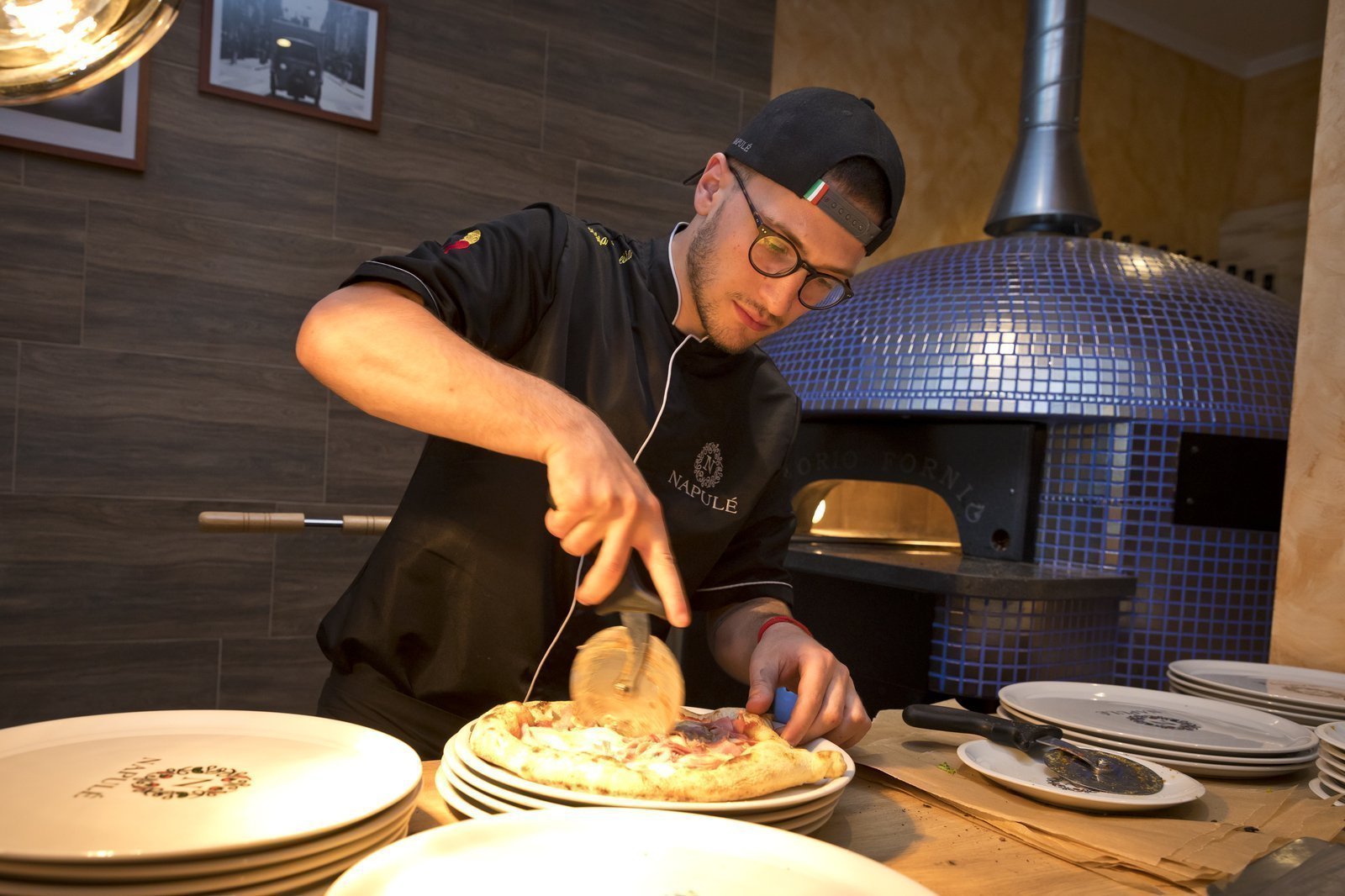 Pizzeria Locarno Pizzaiolo am Pizza schneiden am Pizza Holzofen
