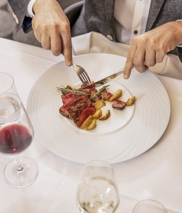 Elegante Männer geniessen ein Dinner in Locarno und lassen sich von einem köstlichen Fleischfest verwöhnen begleited mit einem passenden Rotwein.