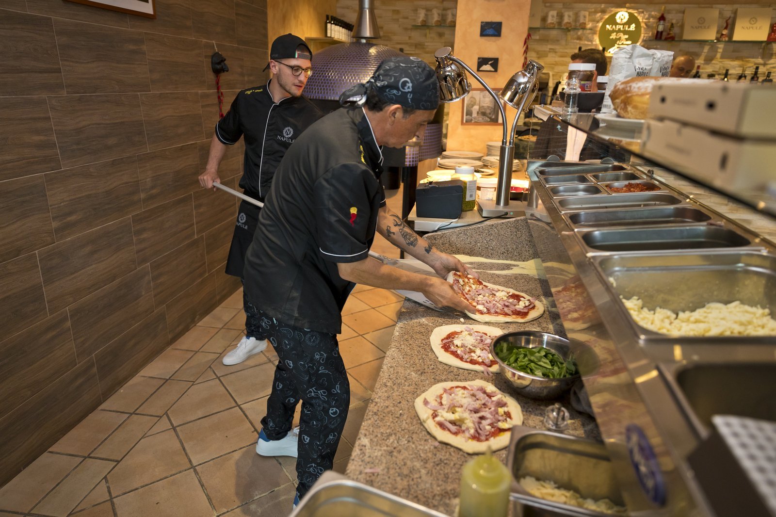 Pizzeria auf neapolitanische Art: Zuschauen in offener Küche beim Meister-Pizzaiolo" Pizzaiolo am Pizza machen auf Neapolitanische Art mit allen Zutaten in offener Küche